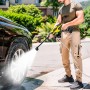 Homme utilisant un nettoyeur haute pression sans fil sur une voiture, jet d'eau puissant, batterie 21V, travail extérieur.