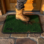 Tapis d’entrée extérieur astroturf twin 45x55 cm vert, emprunté sous une bottine militaire sur une marche en pierre.