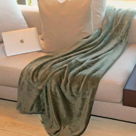 Plaid en microfibre olive posé sur un canapé beige, drapé sur un côté avec un ordinateur portable blanc à côté.
