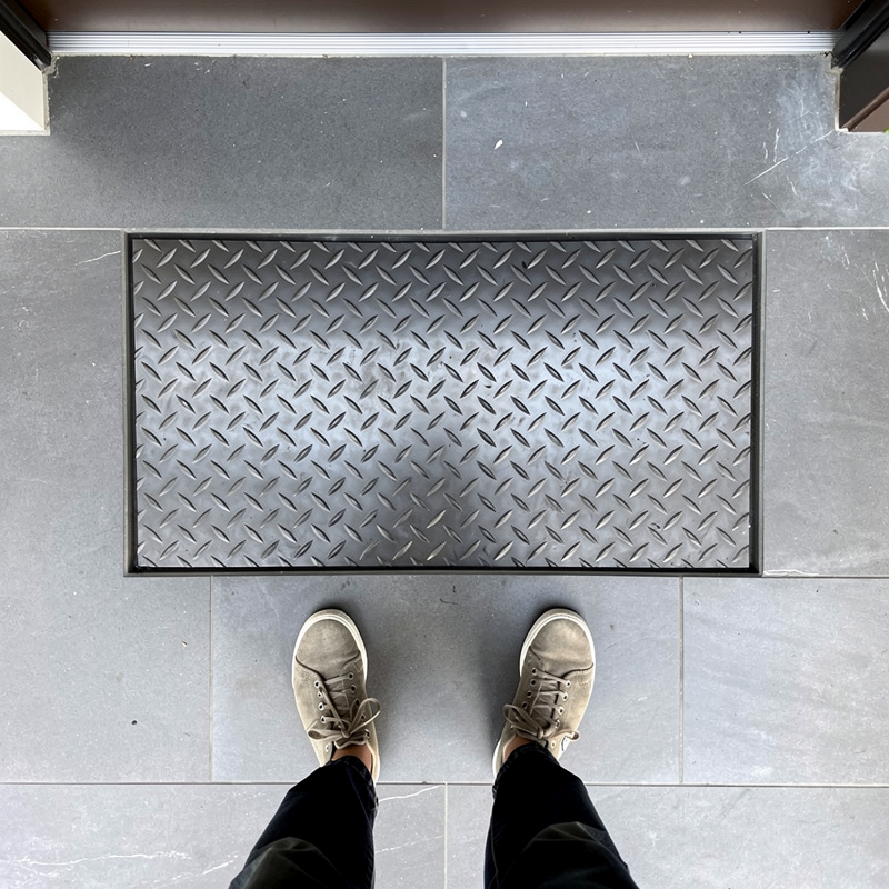 Paillasson encastrable intégré dans un carrelage d'entrée moderne