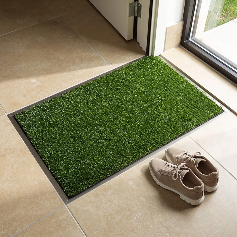 Tapis encastrable en gazon artificiel intégré dans un carrelage d'entrée moderne
